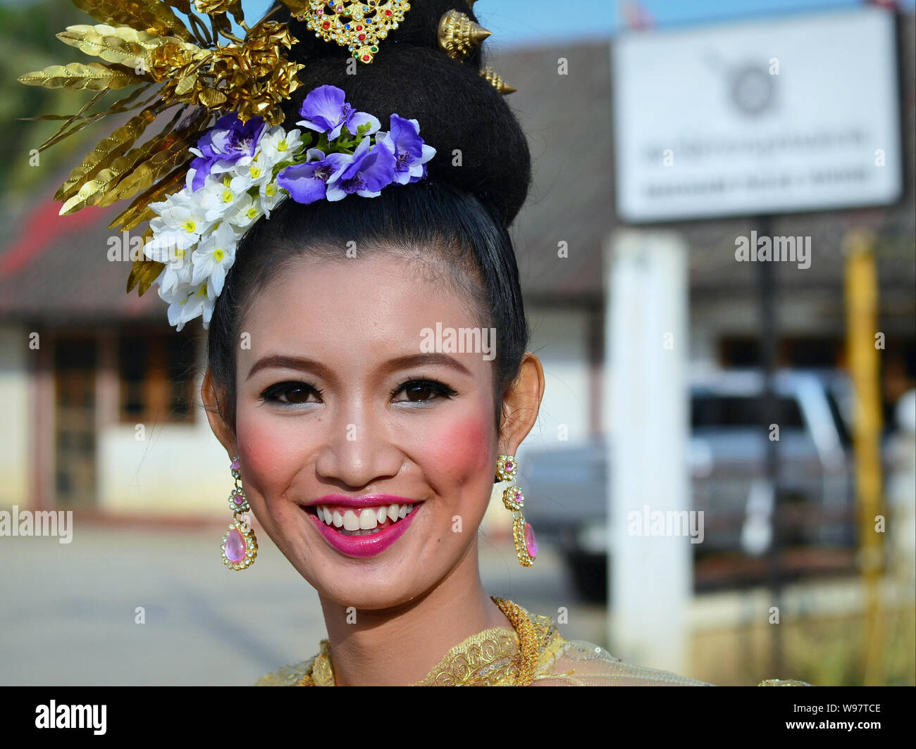 Vestite bella ragazza Thailandese con fiori nei capelli prende parte del villaggio Lanna storico street parade e sorrisi per la fotocamera. Foto Stock