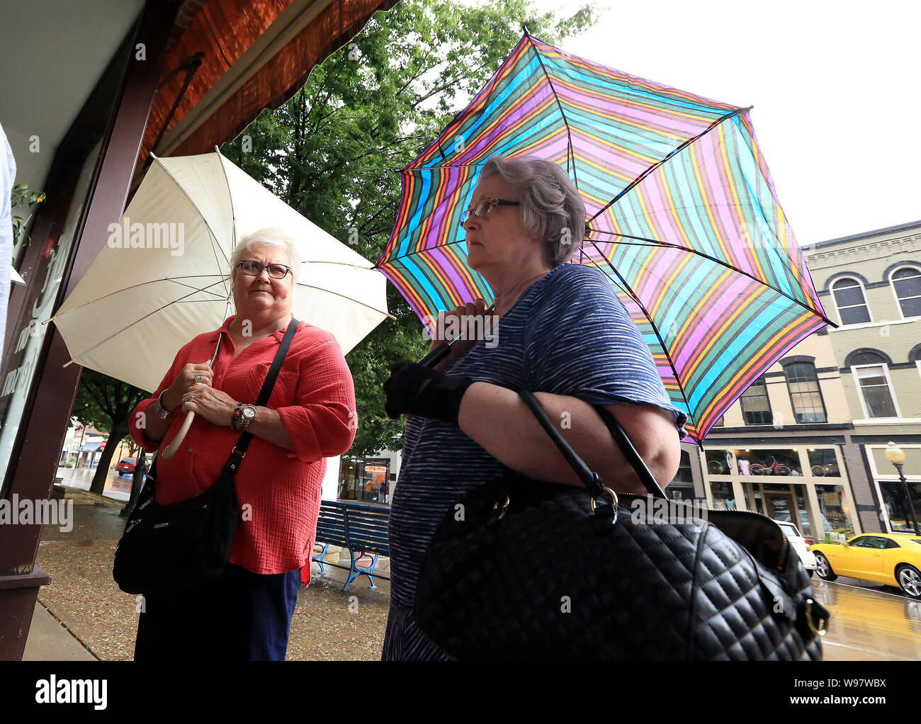 Burlington, Iowa, USA. 12 Ago, 2019. Nancy Gallentine, a sinistra del Nord inglese e Colette Carroll di Burlington attendere sotto la pioggia prima di cura per la salute tavola rotonda con Kamala Harris presso il loft al primo Regno Chiesa Metodista di Burlington Lunedì, Agosto 12, 2019 Credit: Kevin E. Schmidt/Quad-City volte/ZUMA filo/Alamy Live News Foto Stock