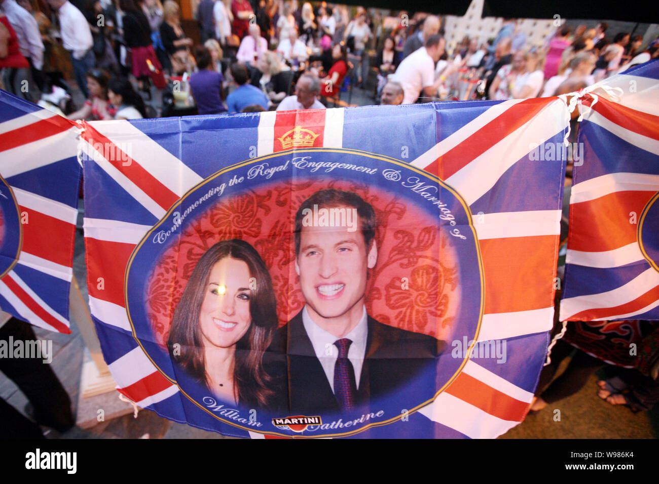 Bandiere di British il principe William e la sua fidanzata Kate Middleton sono ritratte mentre i cittadini stranieri stanno a guardare la trasmissione in diretta della royal weddin Foto Stock