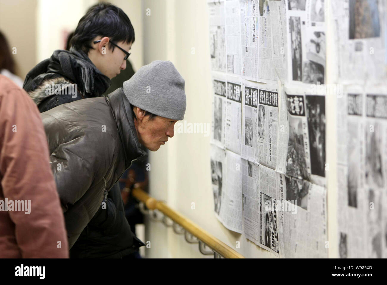 Locali residenti giapponese leggere giornali con relazioni sul tsunami devastazione causata dal 9,0-terremoto di magnitudine di Sendai, Giappone, 13 marzo 201 Foto Stock