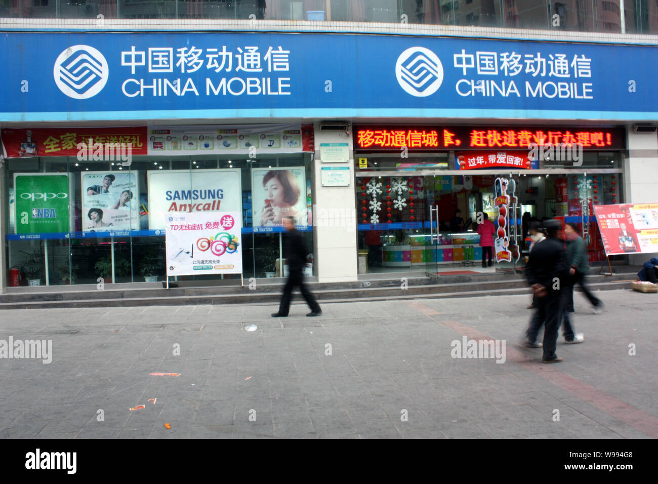 I residenti locali a piedi passato un ramo di China Mobile a Chongqing Cina, 23 febbraio 2011. China Mobile Ltd., i mondi più grande operatore wireless b Foto Stock