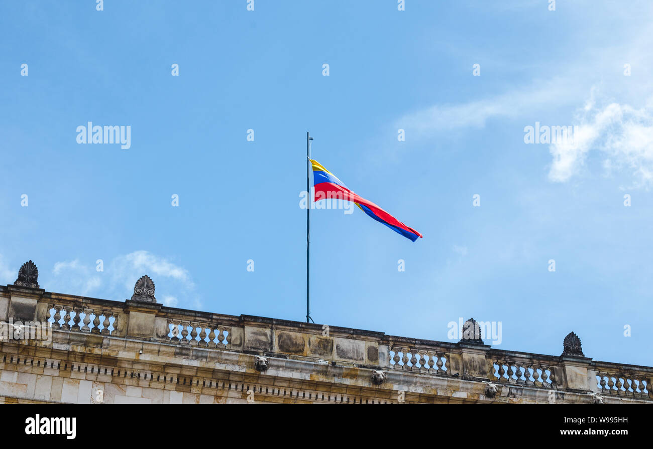 Giallo, blu e rosso striato bandiera colombiana vola al di sopra di un palazzo del governo di Bogotá, in Colombia su una soleggiata giornata estiva Foto Stock