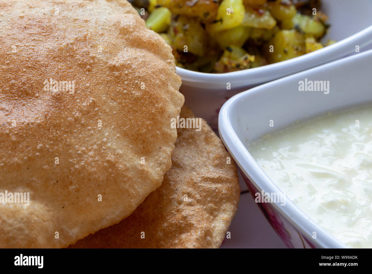 Il Puri Bhaji, Masala, Aloo Sabzi fry servita con fried puri o di pane indiano e latticini, il fuoco selettivo. Foto Stock