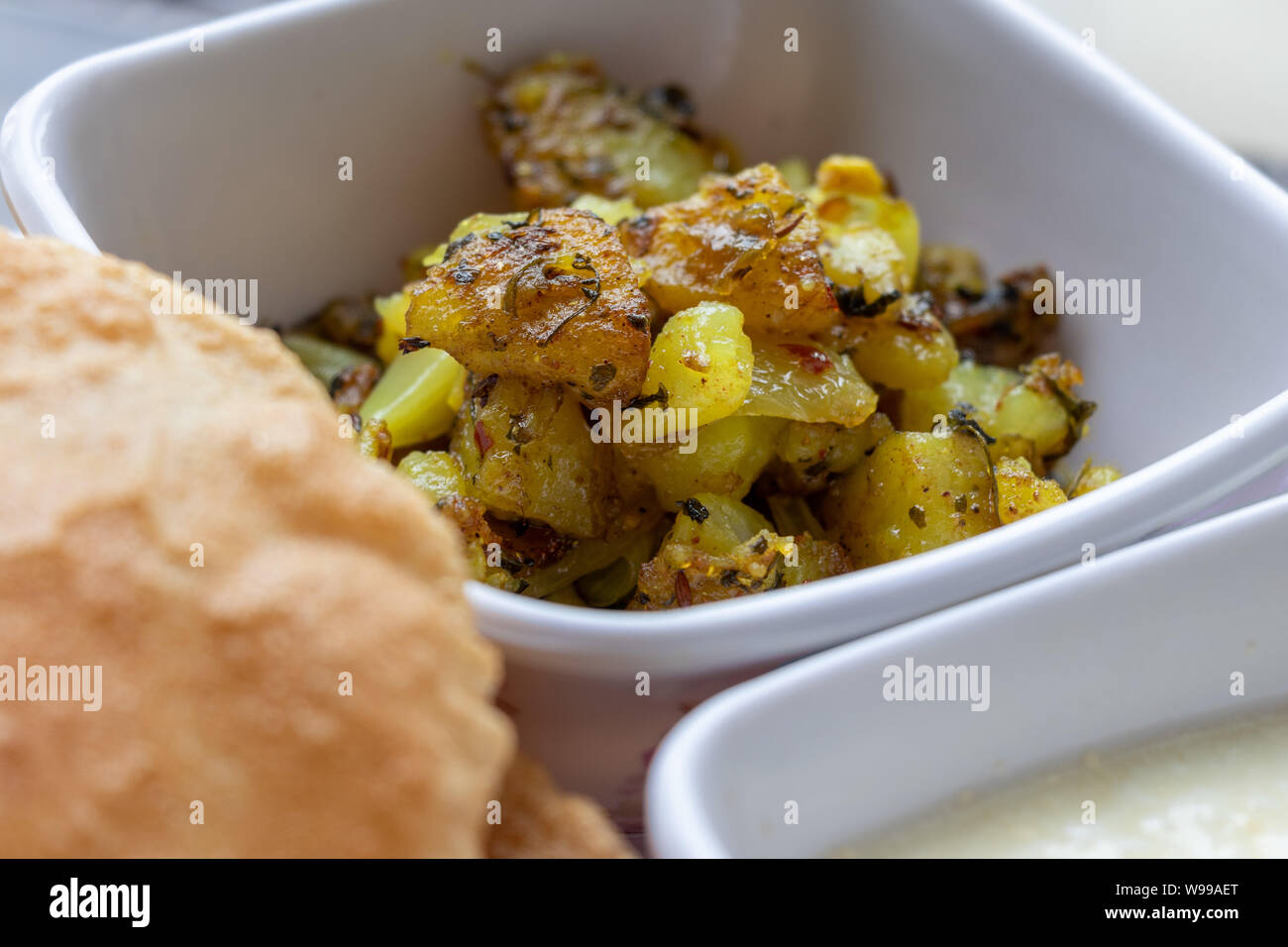 Il Puri Bhaji, Masala, Aloo Sabzi fry servita con fried puri o di pane indiano e latticini, il fuoco selettivo. Foto Stock