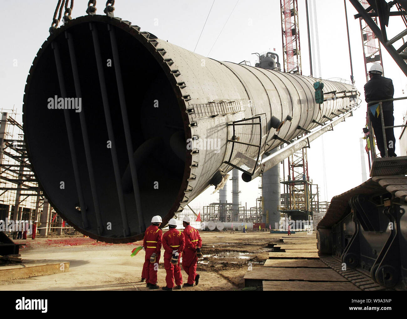 --FILE--lavoratori cinesi guardare una installazione sollevato presso il cantiere per la costruzione di un impianto di etilene di Sinopec di Tianjin, Cina, 2 Dicembre 2008 Foto Stock