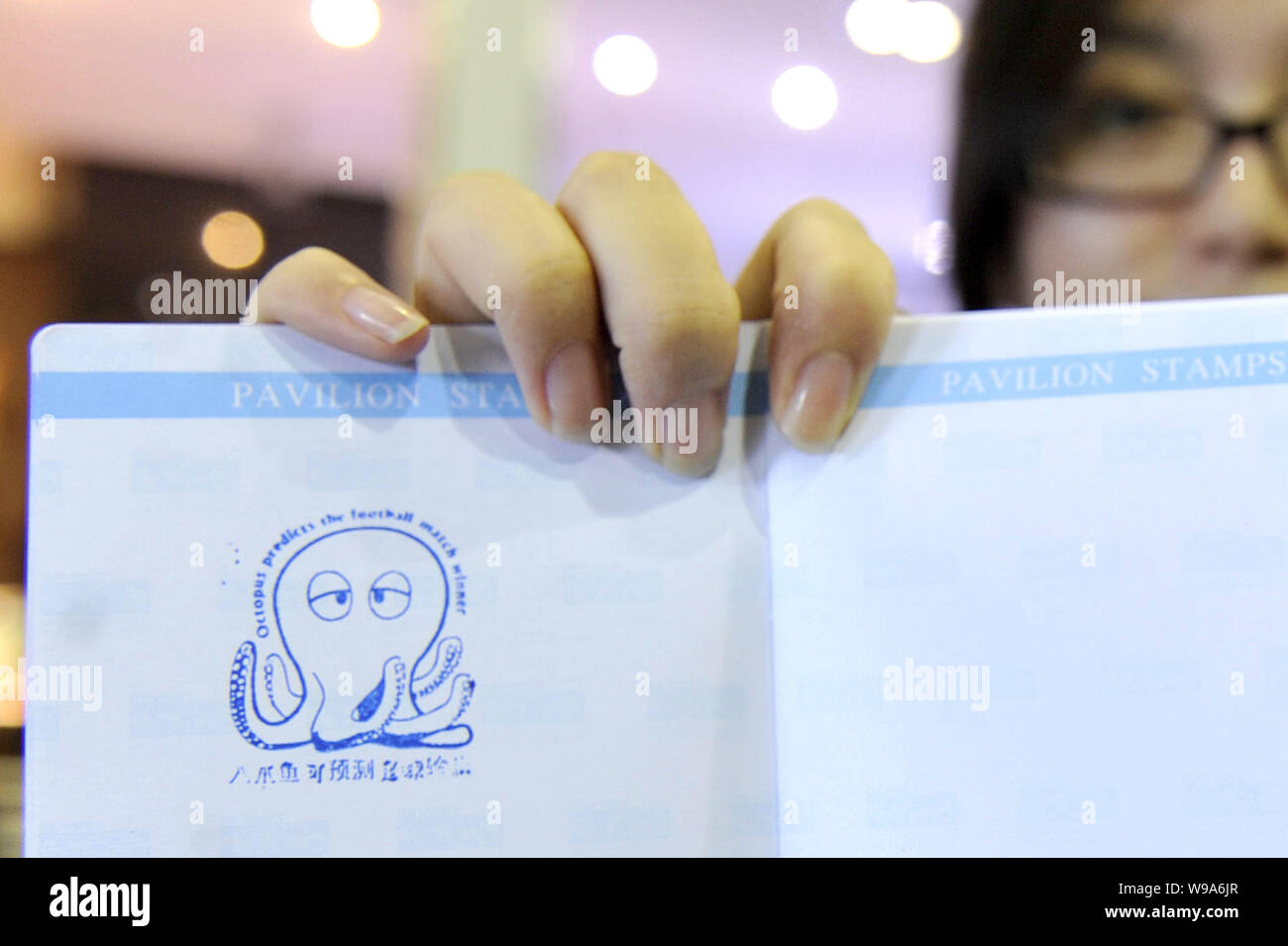 Una donna cinese mostra il passaporto Expo stampigliate con il polpo lucky guarnizione di tenuta a livello del DEVNET (lo sviluppo internazionale delle informazioni di associazione di rete) Foto Stock