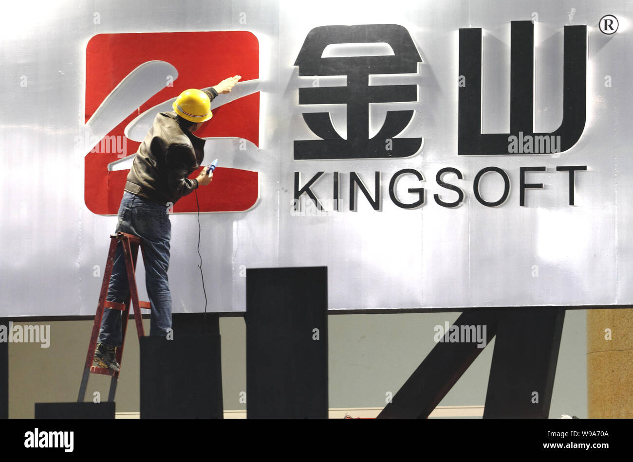 Un lavoratore cinese decora il logo di Kingsoft presso lo stand di Kingsoft Corporation prima dell'apertura del 8° International Digital Content Expo, anche Foto Stock