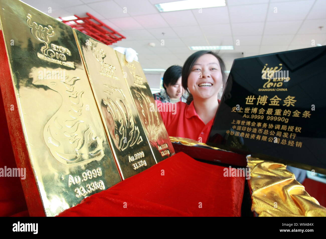 Un dipendente cinese mostra tre Shanghai Expo-tema oro bar in un mondo Expo negozio in franchising in Cina a Shanghai, 12 maggio 2010. I tre oro puro b Foto Stock