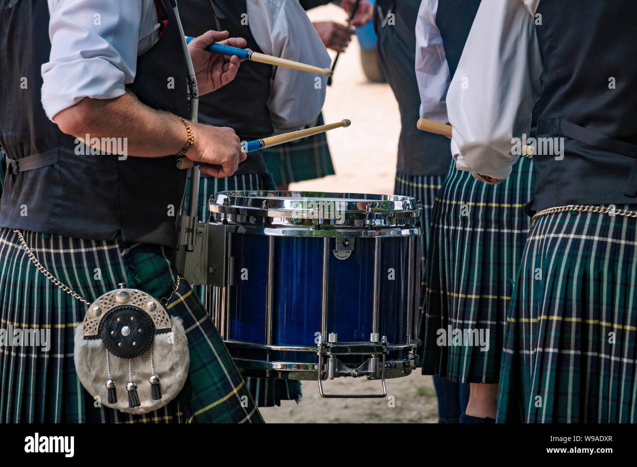 Primo piano del tradizionale scozzese del tamburo e le mani di un batterista che indossa kilt nella banda scozzese giocando all'esterno. Foto Stock