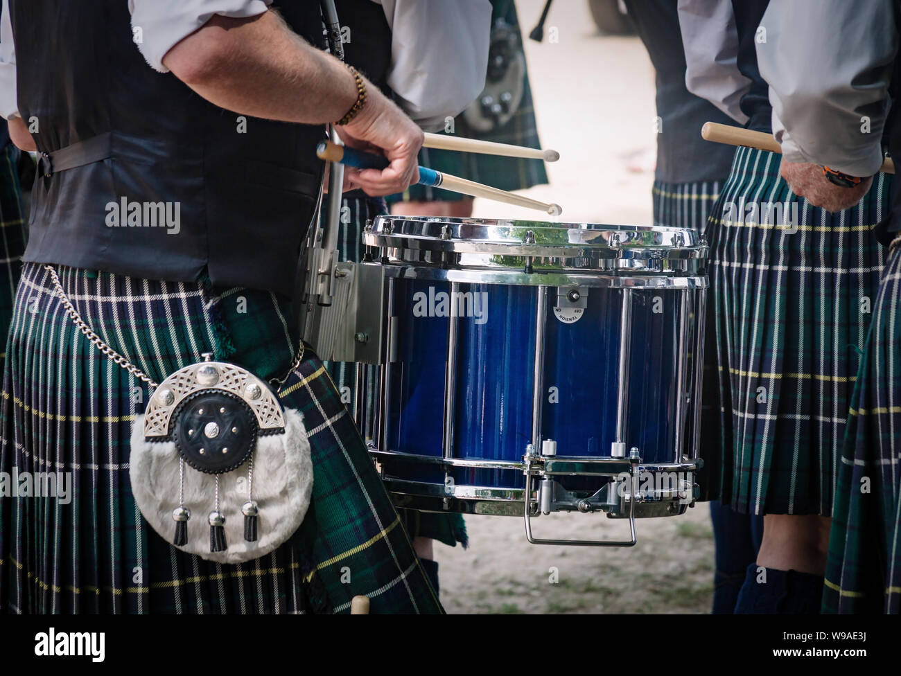 Primo piano del tradizionale scozzese del tamburo e le mani di un batterista che indossa kilt nella banda scozzese giocando all'esterno. Foto Stock