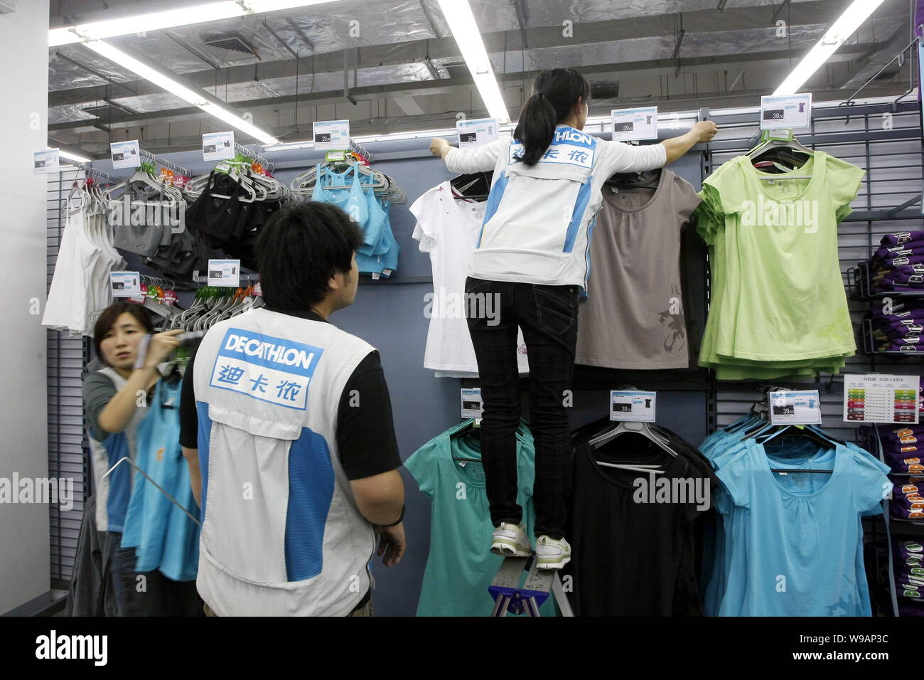 --FILE--dipendenti cinesi riagganciare sportswears in un negozio Decathlon di Pudong, Shanghai, Cina, 19 aprile 2010. L'Unione sportiva rivenditore di materiali di consumo Foto Stock