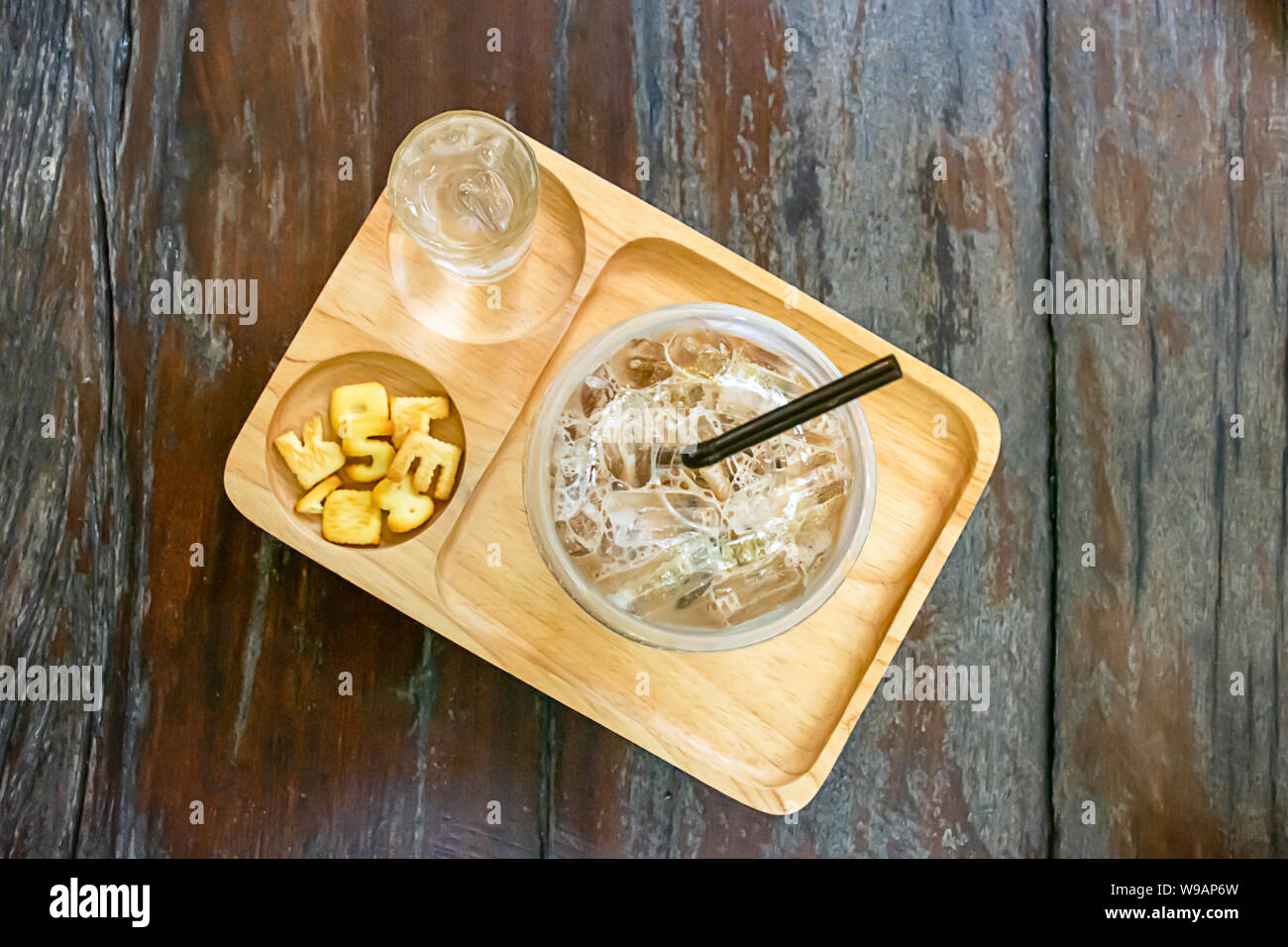 Bicchiere di caffè freddo , acqua e pane che ha più numeri e Ze nel legno del vassoio sul tavolo. Foto Stock
