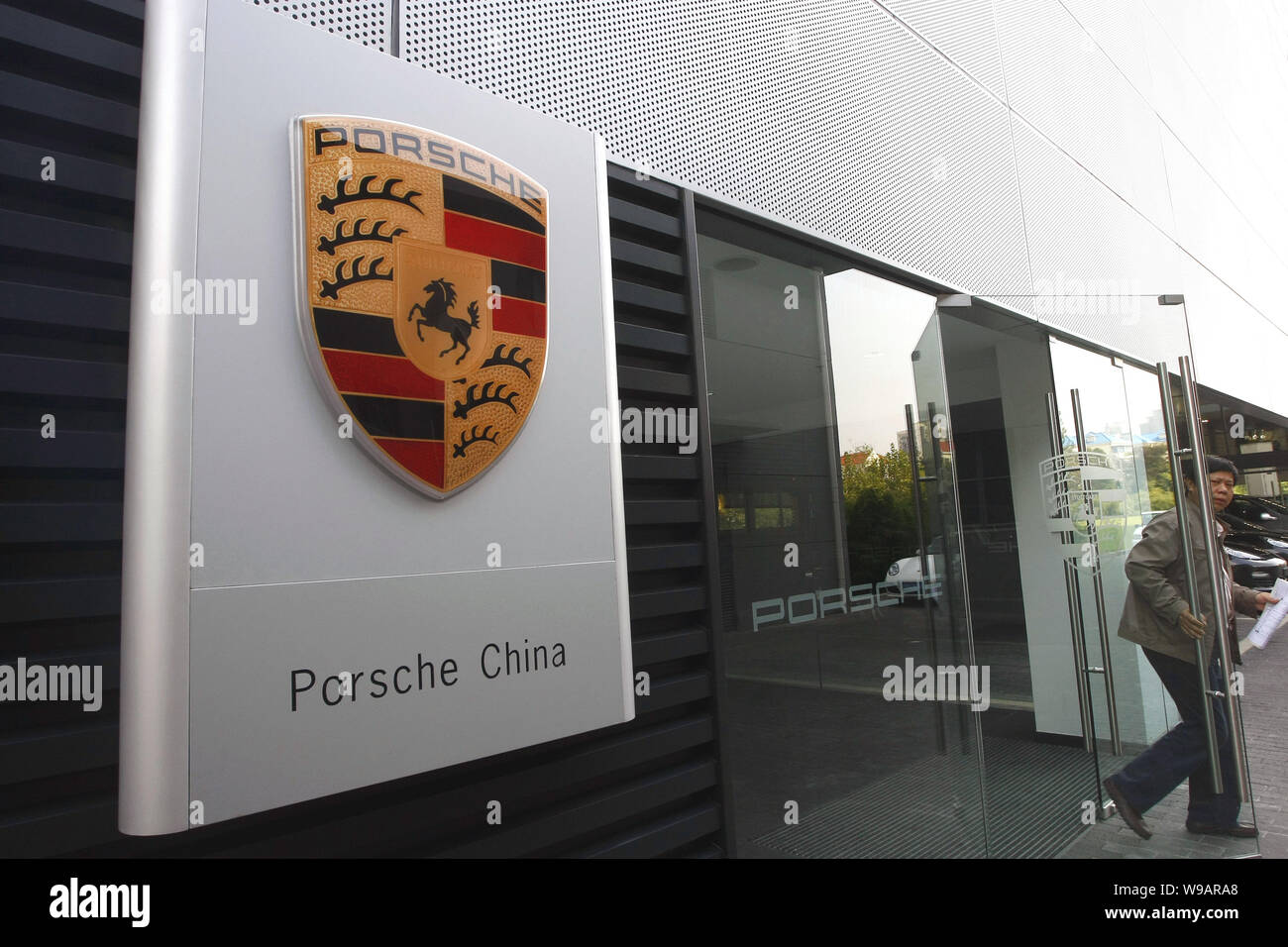 Un personale cinese passeggiate fuori del primo outlet store di Porsche in Cina a Shanghai, 4 novembre 2010. Tedesco sports car maker Porsche AG ha recentemente ope Foto Stock