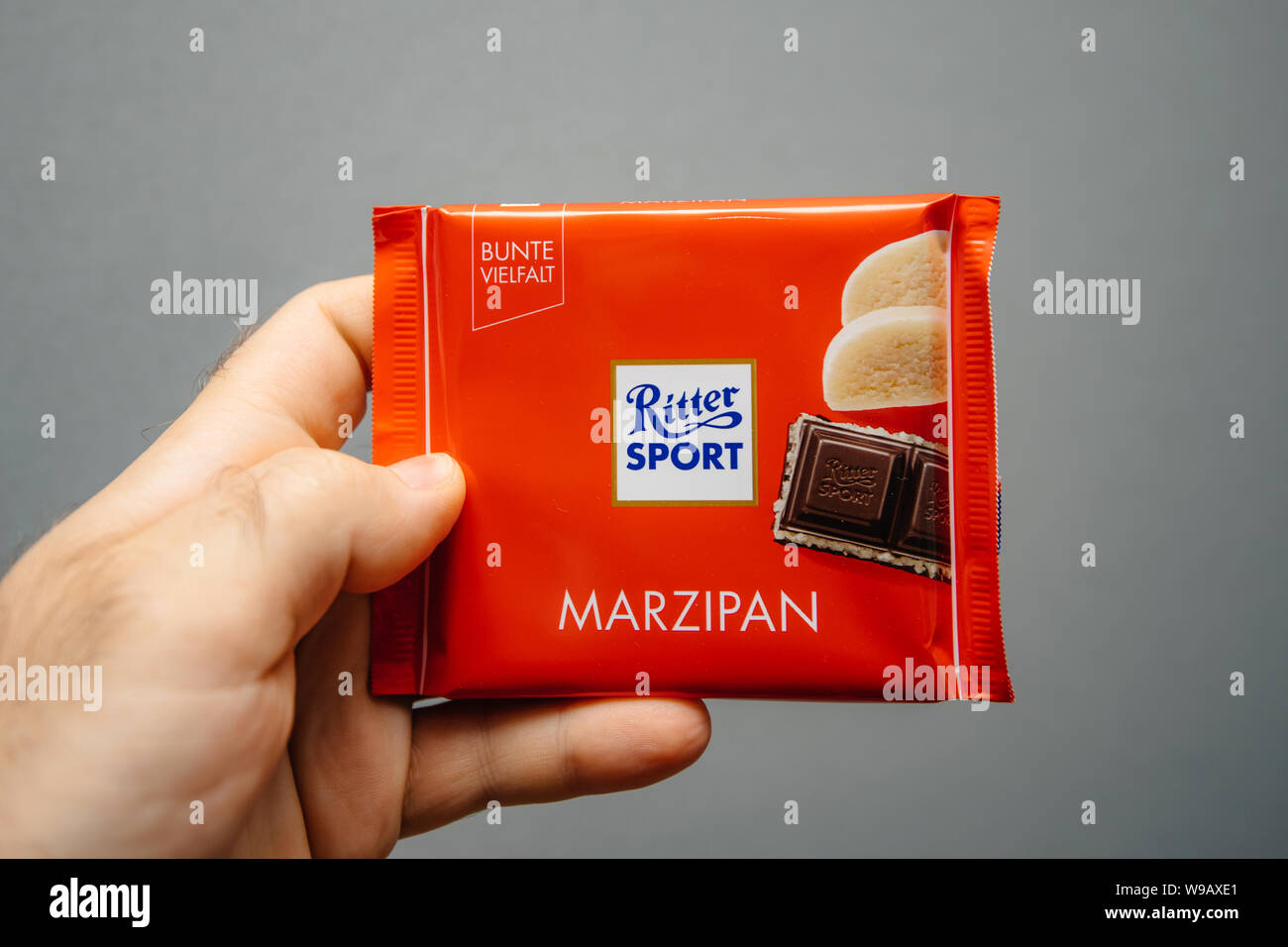 Parigi, Francia - Apr 27, 2019: Man mano che tiene la deliziosa Ritter Sport con cioccolato al sapore di marzapane contro uno sfondo grigio Foto Stock