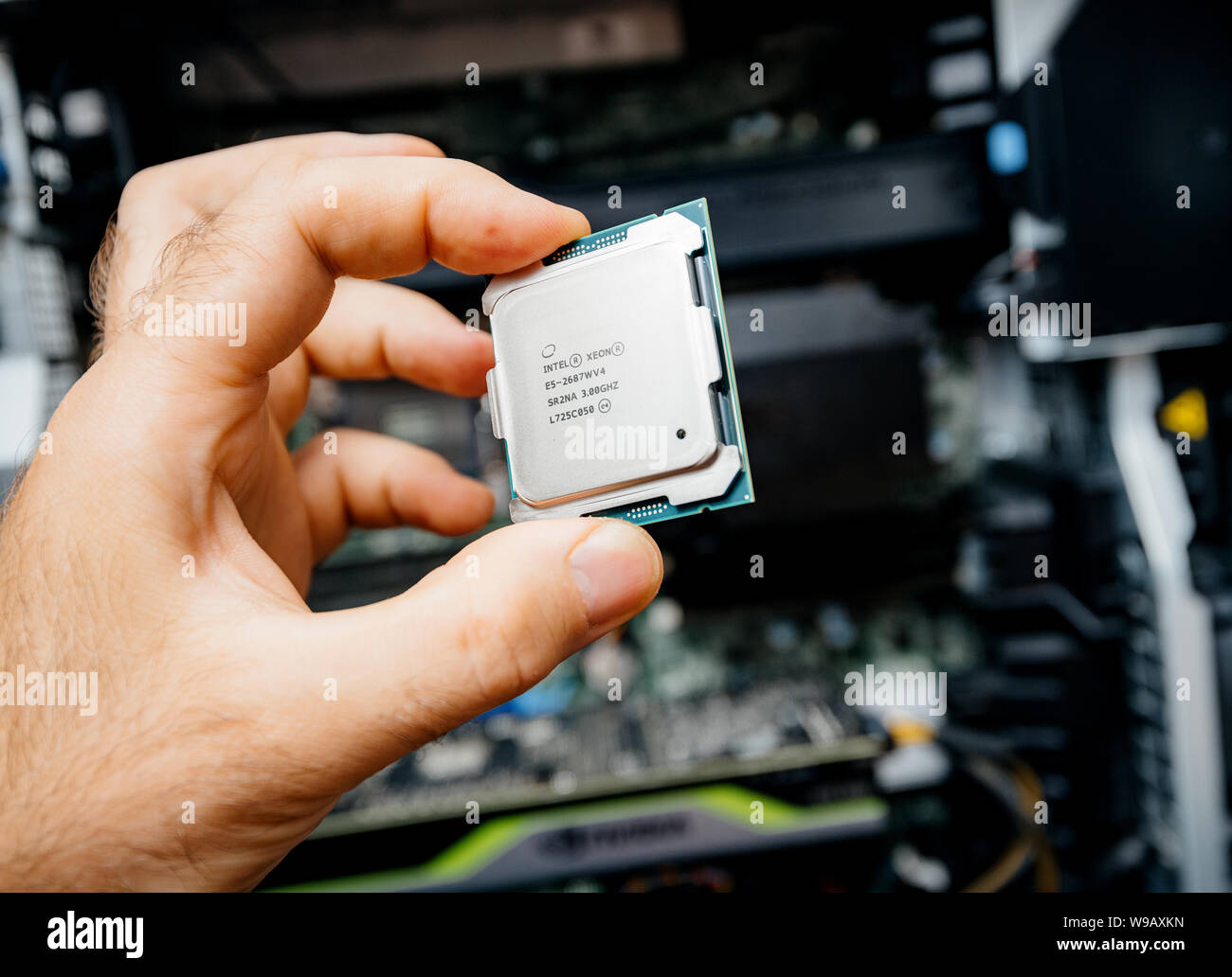 Parigi, Francia - 31 Maggio 2019: vista laterale di ingegnere maschio mano azienda nuova professionale Intel Xeon E5-2687w v4 processore CPU con una workstation Dell Precision in background Foto Stock