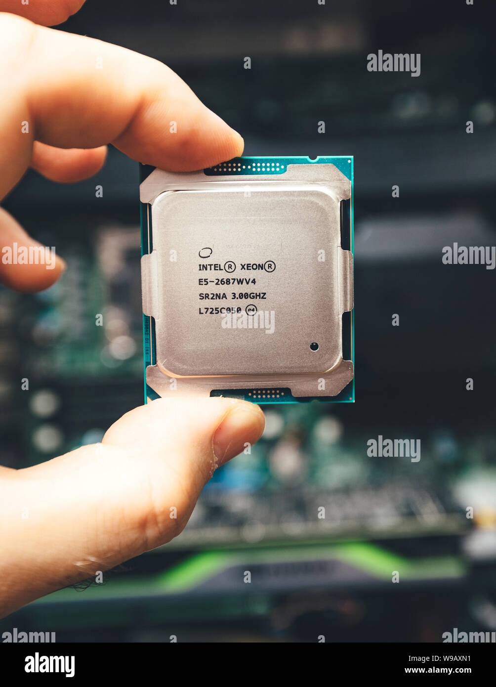 Parigi, Francia - 31 Maggio 2019: vista frontale di ingegnere maschio mano azienda nuova professionale Intel Xeon E5-2687w v4 processore CPU con una workstation Dell Precision sullo sfondo - Immagine verticale Foto Stock