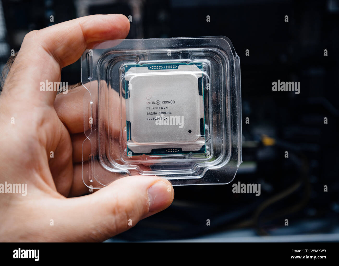Parigi, Francia - 31 Maggio 2019: Close-up di ingegnere maschio mano azienda nuova professionale Intel Xeon E5-2687w v4 processore CPU in blister in plastica unboxing con Dell Precision Workstation in background Foto Stock