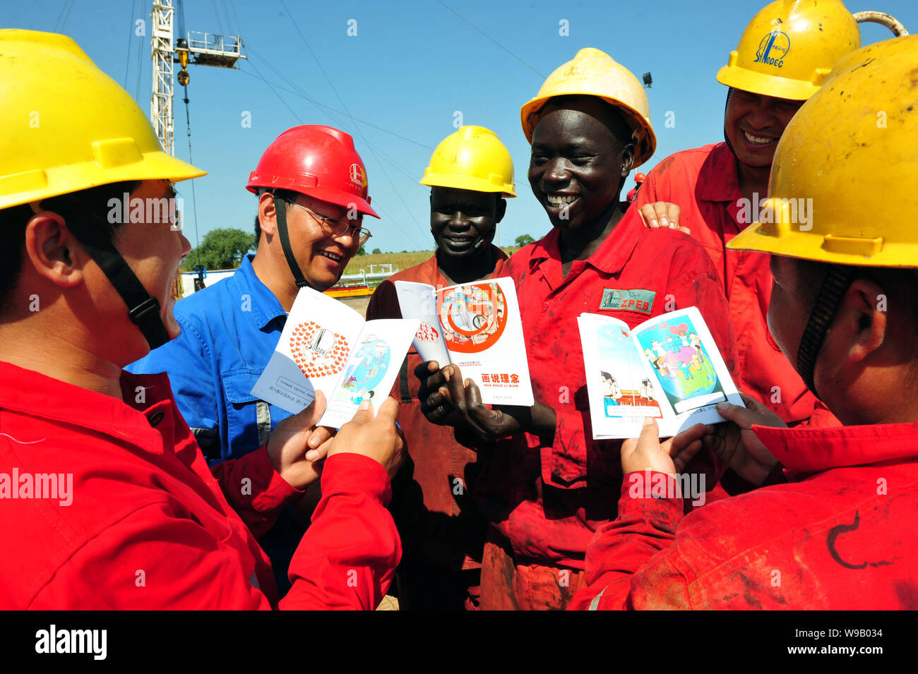 --FILE--lavoratori cinesi dal Zhongyuan Petroleum Exploration Bureau (ZPEB) di Sinopec e lavoratori sudanesi leggere cartoon libri in un campo petrolifero in t Foto Stock