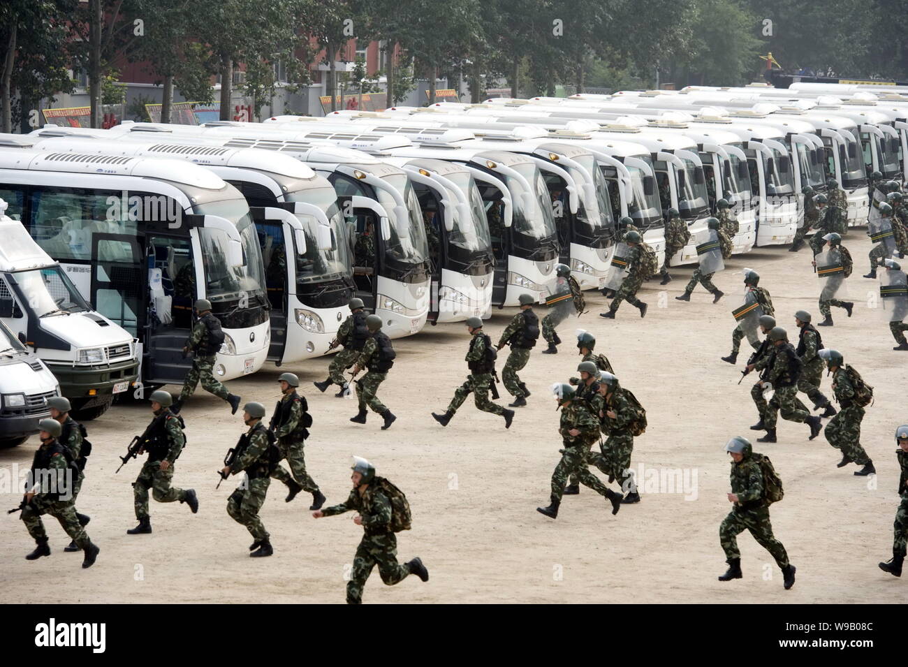 Cinese poliziotti paramilitari rush per gli autobus durante una distribuzione trapano a Pechino in Cina, 2 settembre 2010. La polizia di Pechino autorità detenevano 8 dr Foto Stock