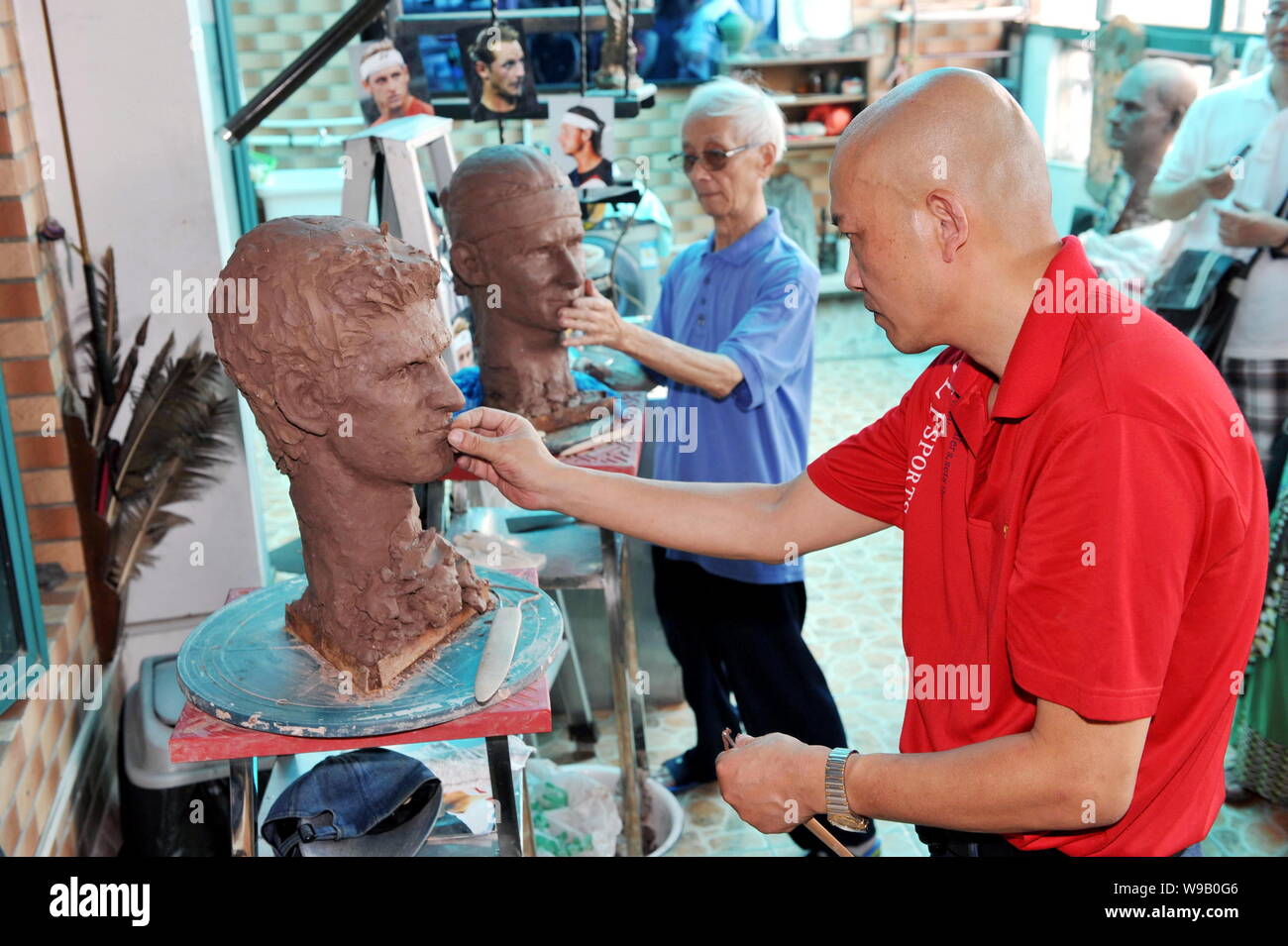 Il 91-anno-vecchio scultore cinese Chen Daotan, indietro e suo figlio Chen Haiyan scolpire il Guerriero di terracotta statue di Argentina tennis giocatore David Nalband Foto Stock