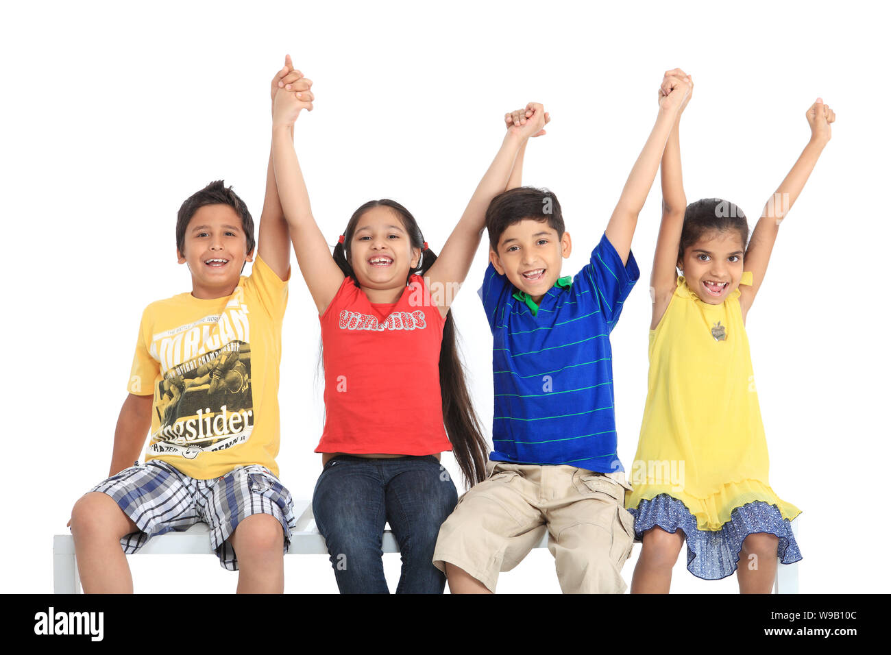 Gruppo di bambini seduti insieme con le braccia sollevate Foto Stock