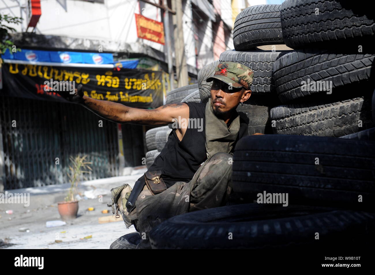 Un Thai anti-government protester si nasconde dietro la parete dei pneumatici sulla strada a Bangkok, Thailandia, 17 maggio 2010. Foto Stock