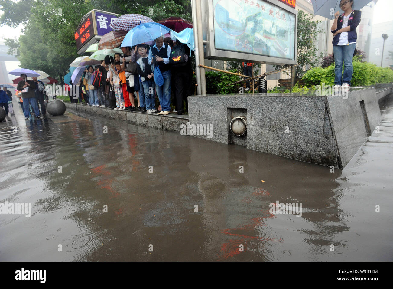 Residente locale stand su parterres fioriti da una strada allagata dopo forti piogge a Wuhan, porcellane centrale provincia di Hubei, 16 maggio 2010. Più heavy rain è exp Foto Stock