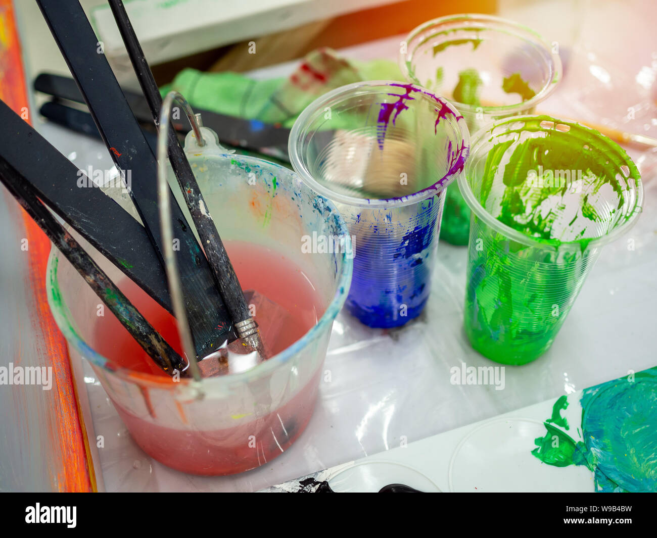 Artista pennelli per dipingere in bianco secchio di acqua, colore acrilico  in bicchieri di plastica in arte studio Foto stock - Alamy