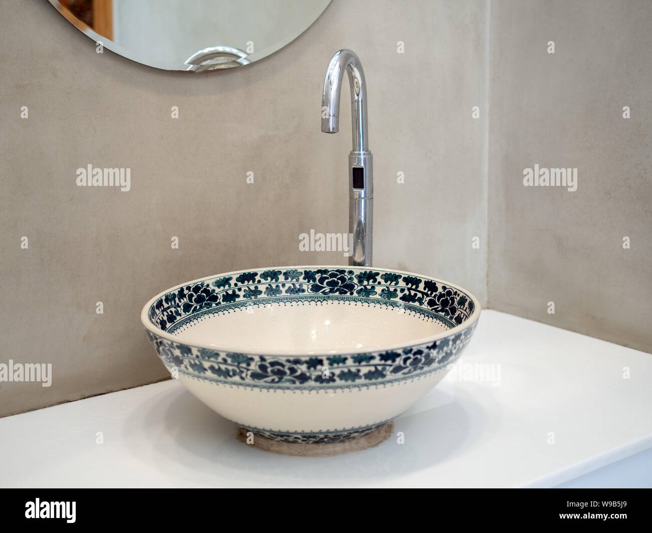 Pulire stile loft bagno interno con lavandino in porcellana rubinetto lavabo in marmo bianco ripiano e specchio rotondo sulla parete in calcestruzzo dello sfondo. Foto Stock