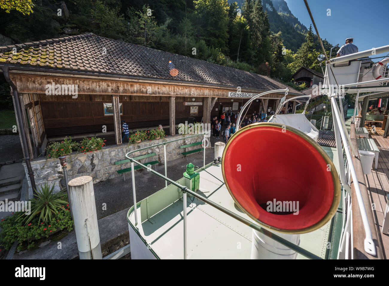 Pontile "Giessbach-See' presso il Lago di Brienz visto da di steamboat 'Lötschberg' con il capitano da dietro e persone in attesa di accedere Foto Stock