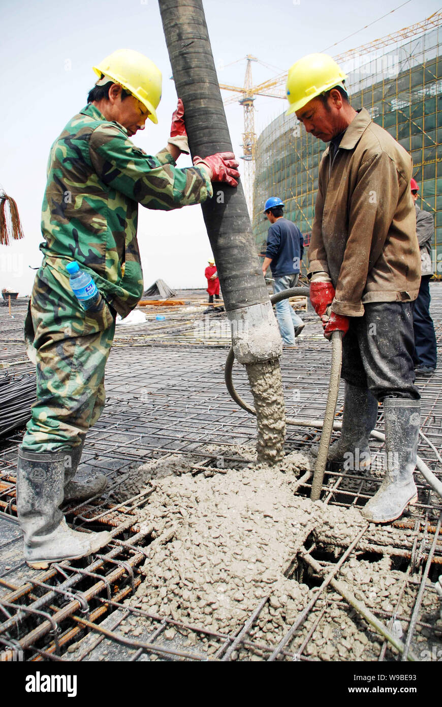 Lavoratori cinesi versare cemento sul sito della costruzione dell'edificio principale dell'Animazione Parco Industriale della Sino-Singapore Tianjin Eco-city in Foto Stock