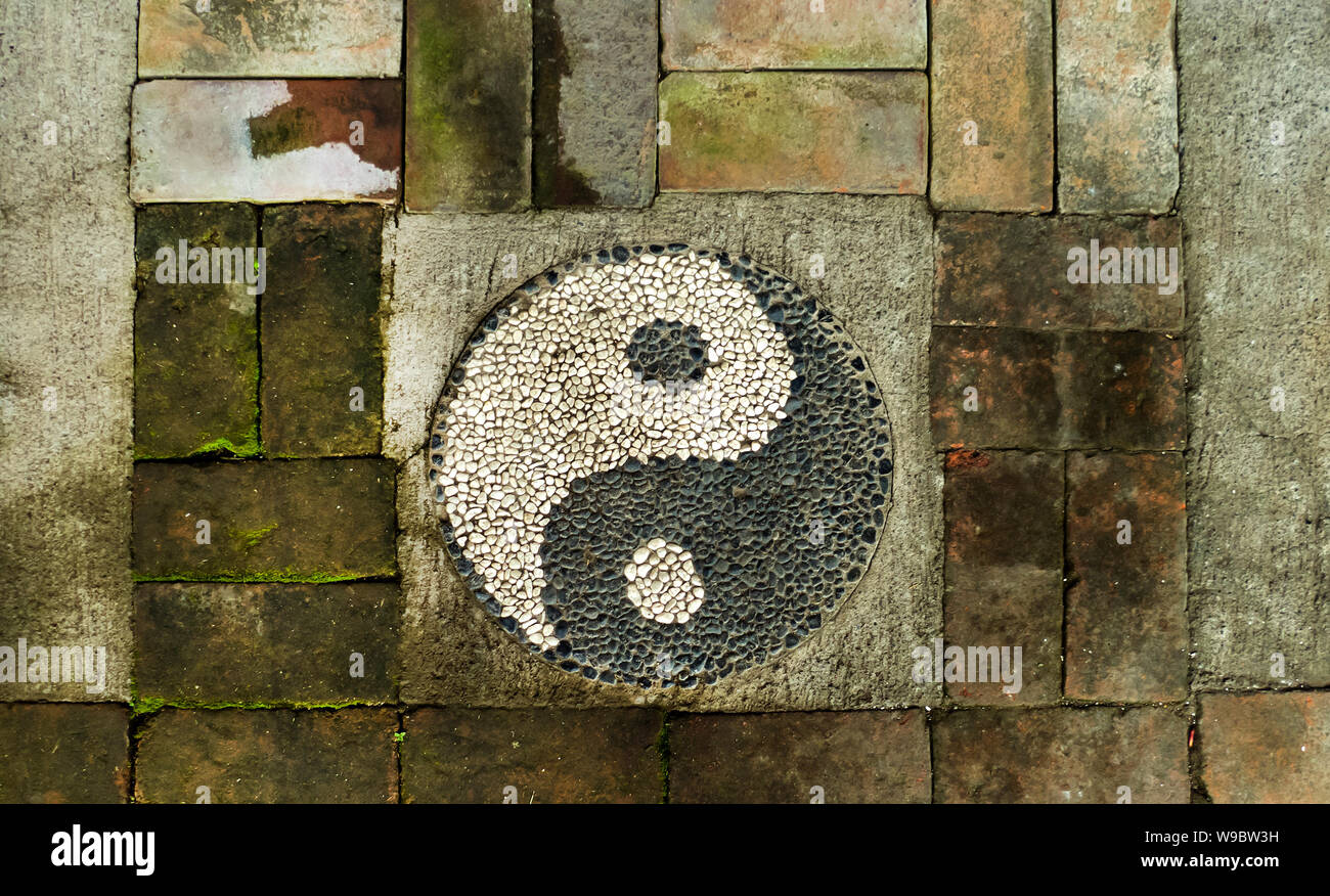 Ying e Yang segno su un weathered muro di mattoni Foto Stock