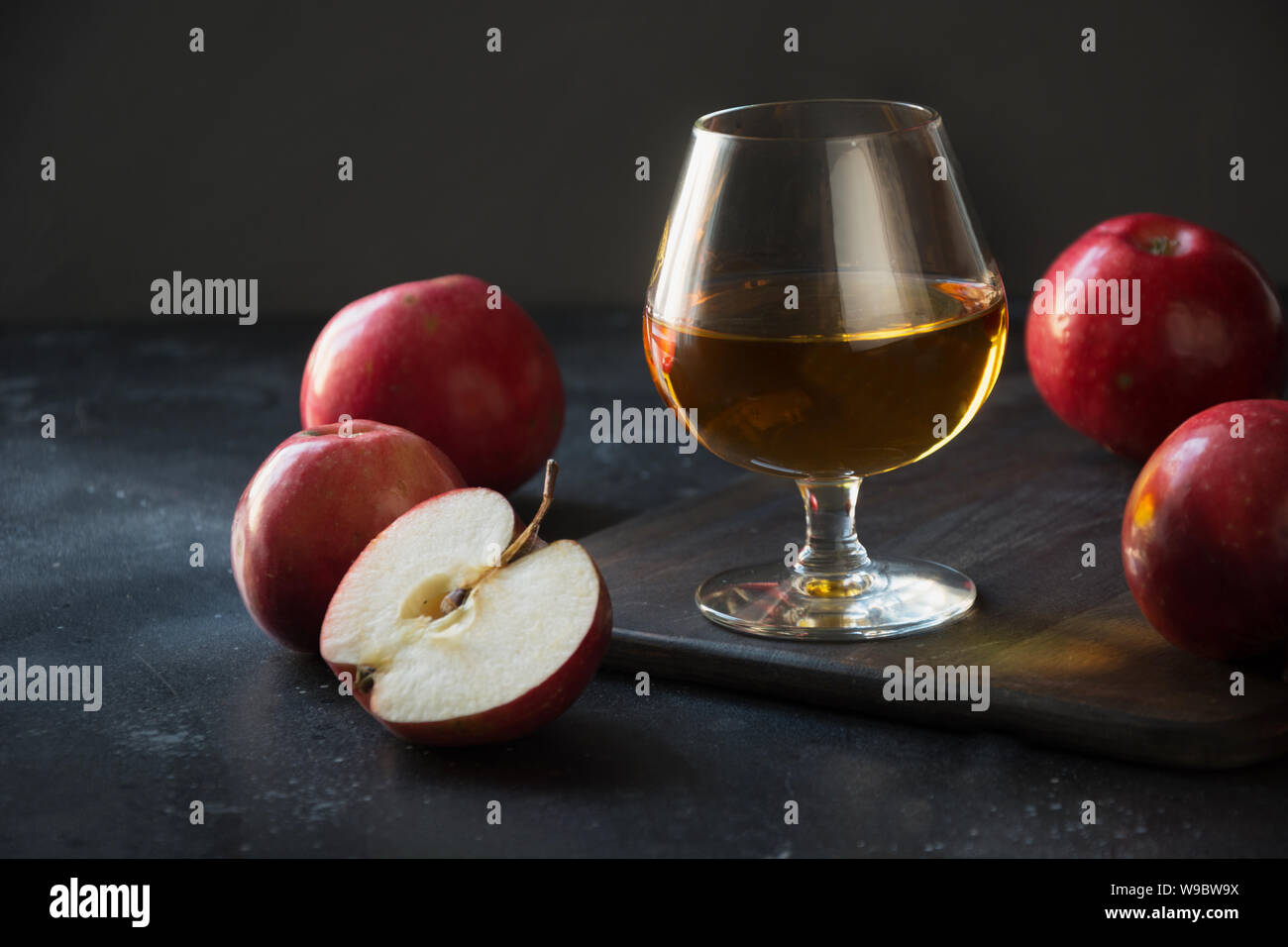 Vetro con calvados brandy e mele rosse su nero. Close up. Foto Stock