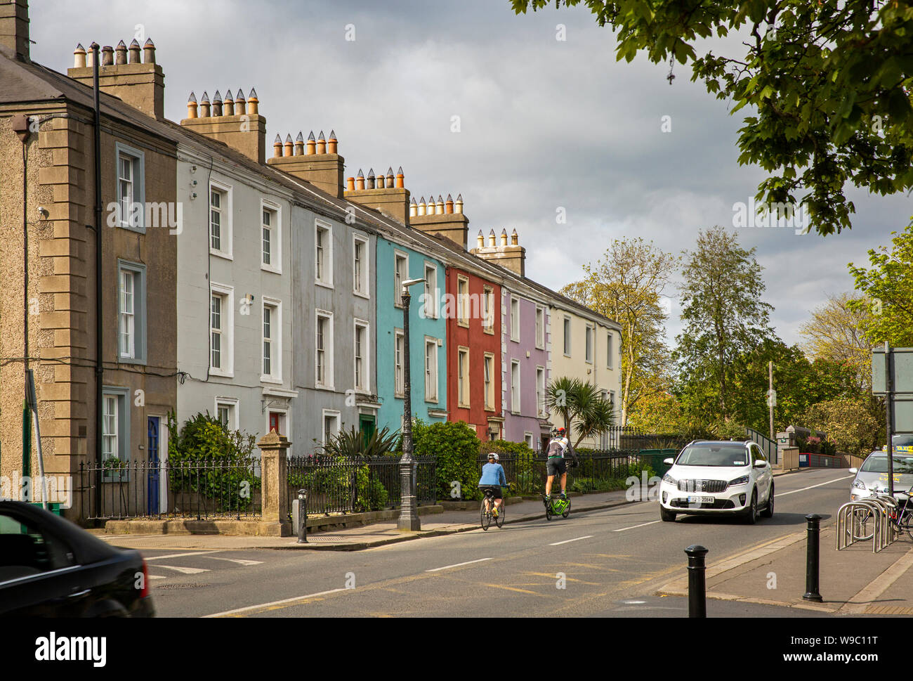 Irlanda, Co Dublin, Malahide, Dublin Road, ciclisti passando terrazza del dipinto in maniera colorata case in stile georgiano Foto Stock
