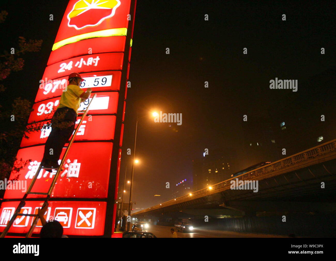 Un lavoratore cinese aggiorna i prezzi del carburante in corrispondenza di una stazione di benzina della CNPC (China National Petroleum Corporation), società madre di PetroChina, a Pechino, Cina Foto Stock