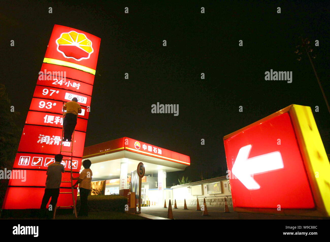 Un lavoratore cinese aggiorna i prezzi del carburante in corrispondenza di una stazione di benzina della CNPC (China National Petroleum Corporation), società madre di PetroChina, a Pechino, Cina Foto Stock