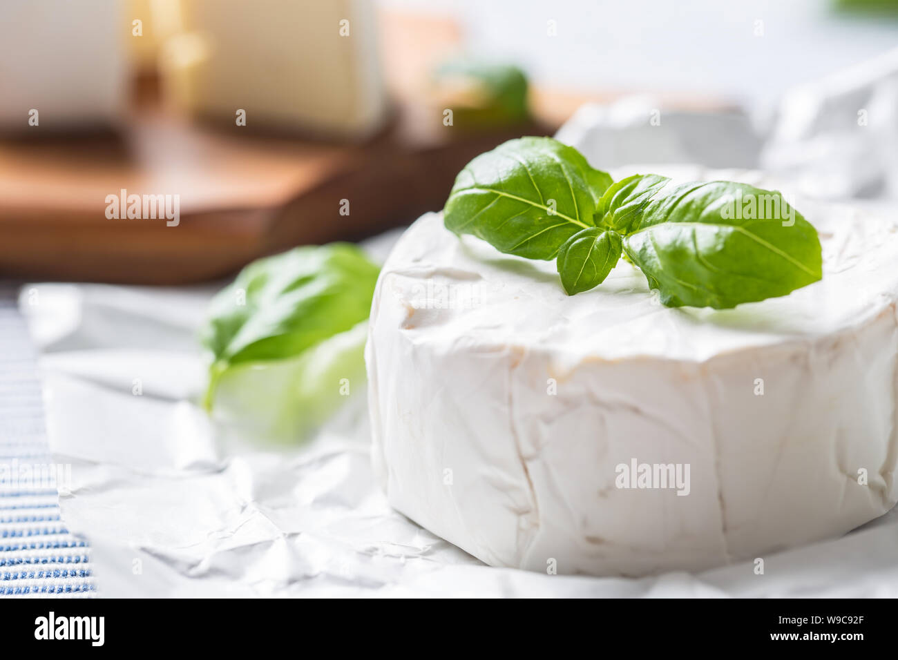 Camembert o formaggio brie con foglie di basilico sul tavolo Foto Stock