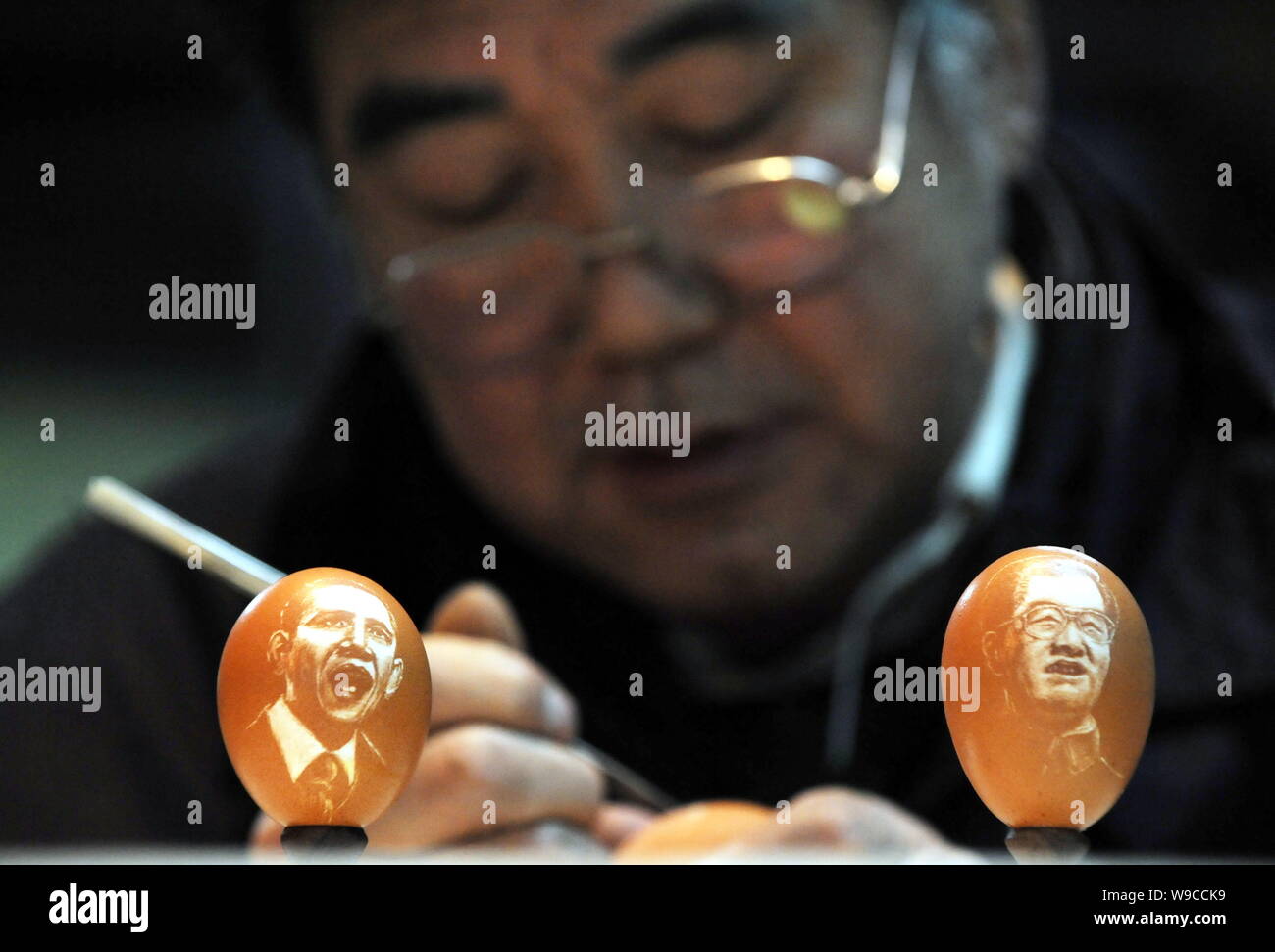 Folk Cinese scultore Kang Yongguo è visto come affettare un uovo di pollo dietro due uova scolpiti con i ritratti del presidente cinese Hu Jintao, destro e Foto Stock