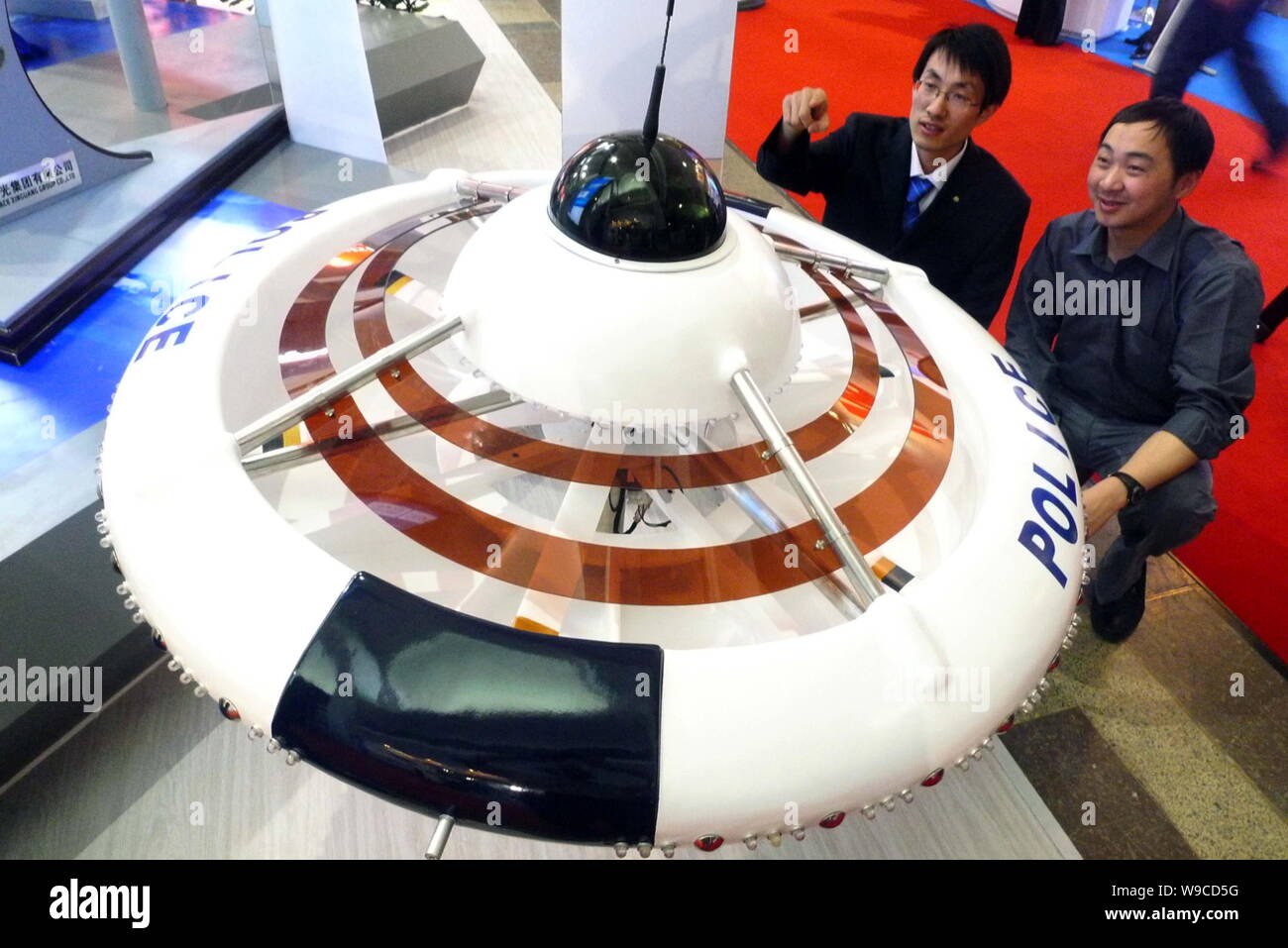 Gli uomini cinesi guardare a un modello di polizia Flying Saucer sul display al terzo la Cina (Pechino) Mostra Internazionale e Simposio sulla cooperazione di polizia e Anti Terro Foto Stock