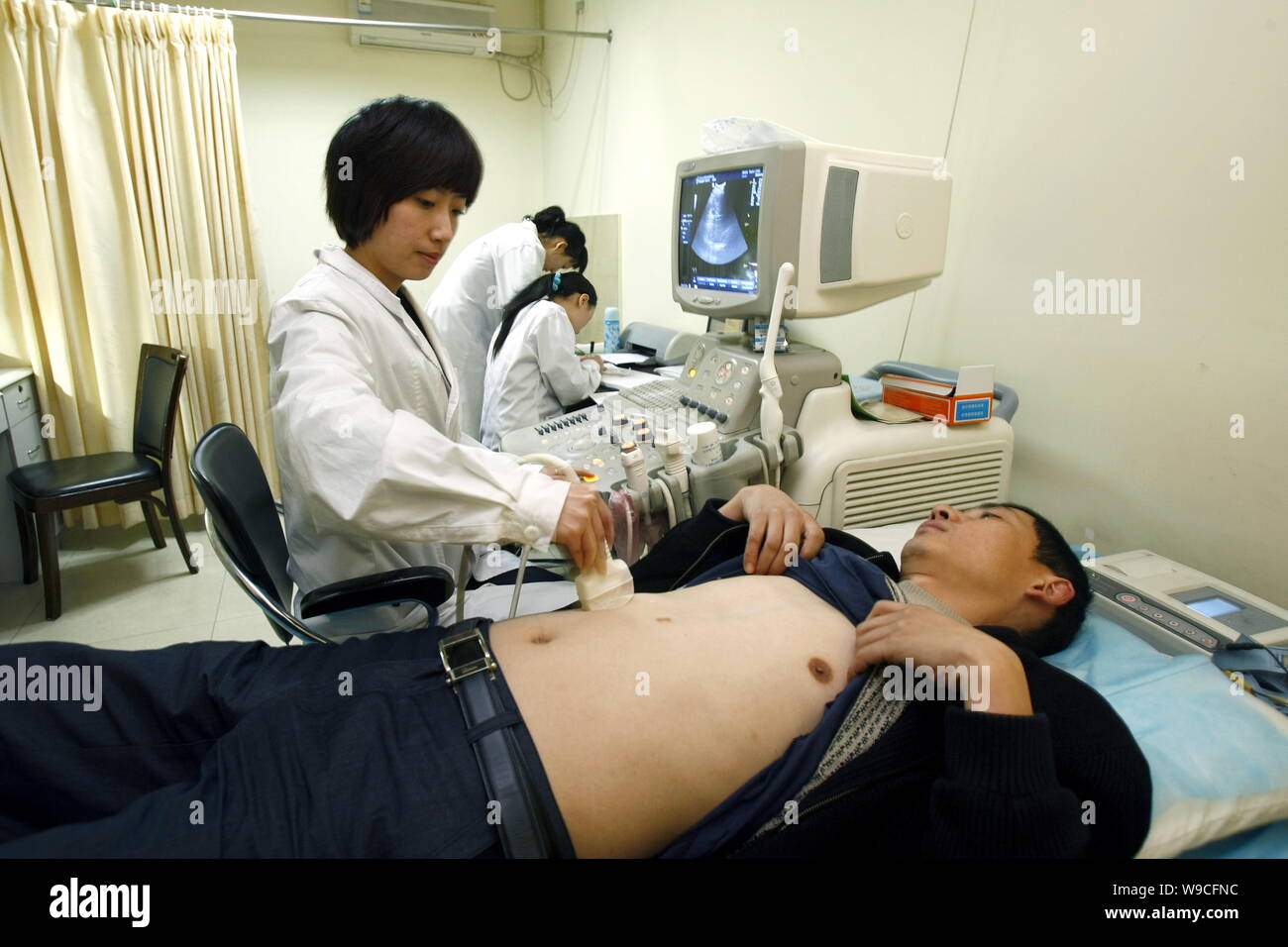 Un medico cinese utilizza un B-ultrosonic scanner per esaminare un uomo in un ospedale di Chongqing Cina, 2 aprile 2009. La Cina mira a rendere le cure sanitarie di base Foto Stock