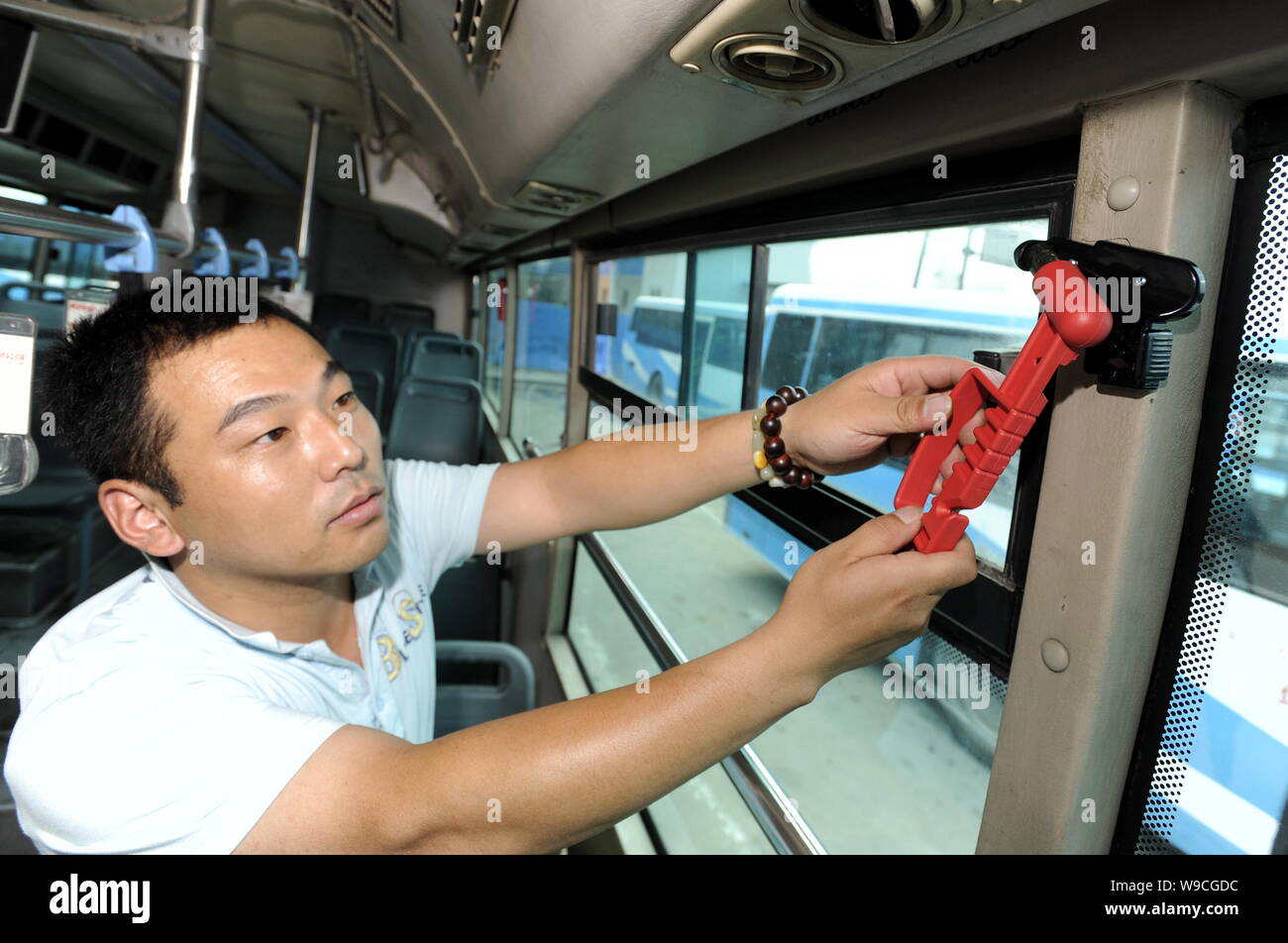 Un bus cinese lavoratore equipaggia un bus con rottura del vetro del martello di emergenza nella città di Nanjing East Chinas provincia dello Jiangsu, giovedì, 11 giugno 2009. Ch Foto Stock
