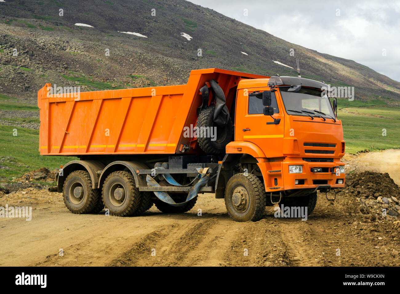 Autocarro con pianale di scarico accende la strada di montagna in costruzione Foto Stock