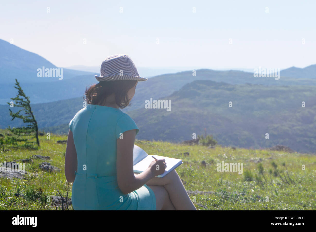 Pittrice fare schizzi in un notebook all'aria aperta in montagna Foto Stock