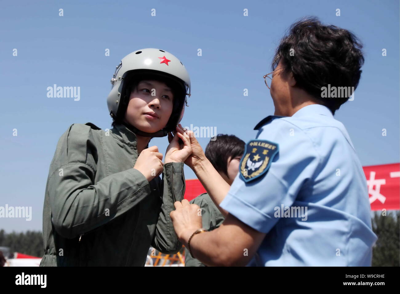 Un veterano pilota femmina, diritto, aiuta una giovane combattente donna piano pilota di indossare il casco pilota durante un nuovo volo abiti cerimonia di consegna presso un'aria Foto Stock