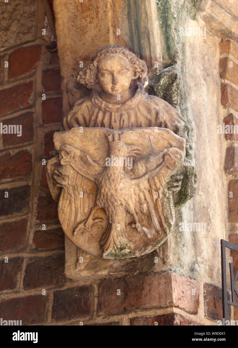 Cracovia. La Polonia. Un stonecrafted figura tenendo la piastra con il bianco aquila, polacco emblema nazionale sulla parete esterna di una delle chiese di te. Foto Stock