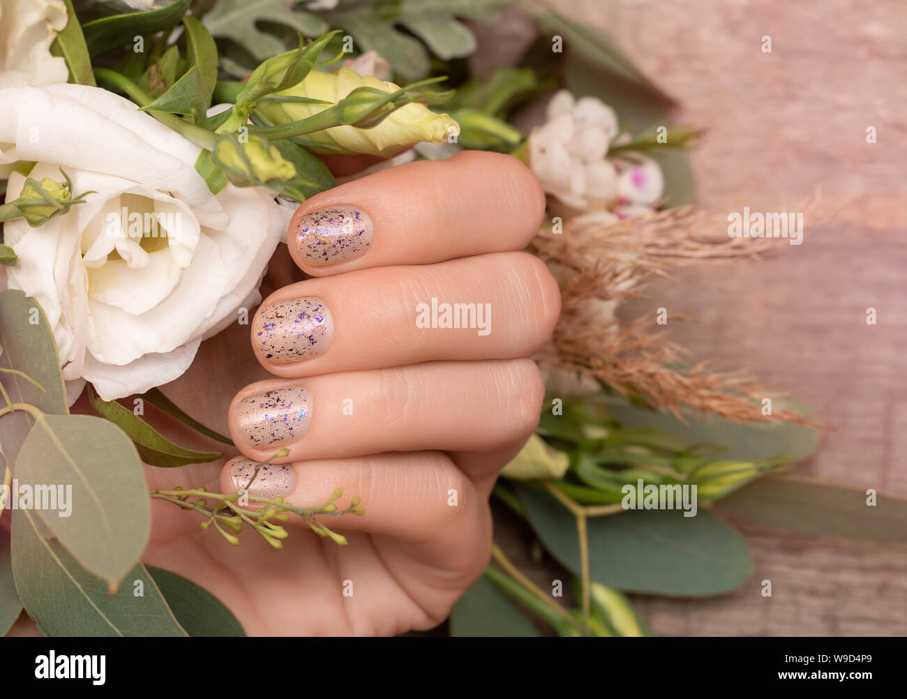Mano femmina con brillantini per unghie azienda progettazione fiori. Foto Stock