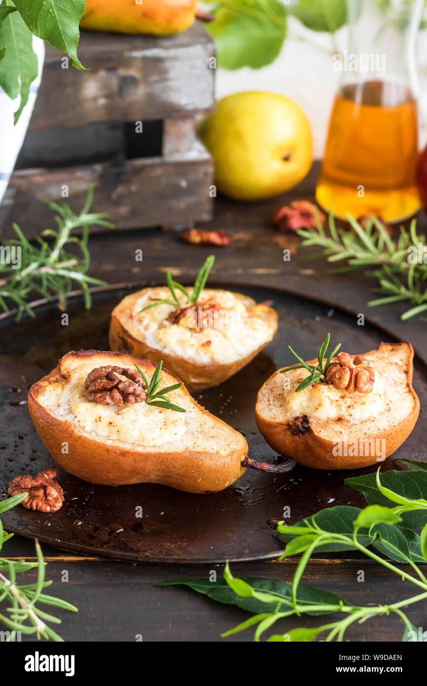 Pere al forno con ripieno di ricotta e noci e miele. Luce dessert sano senza zucchero. Un piatto di riscaldamento. Foto Stock