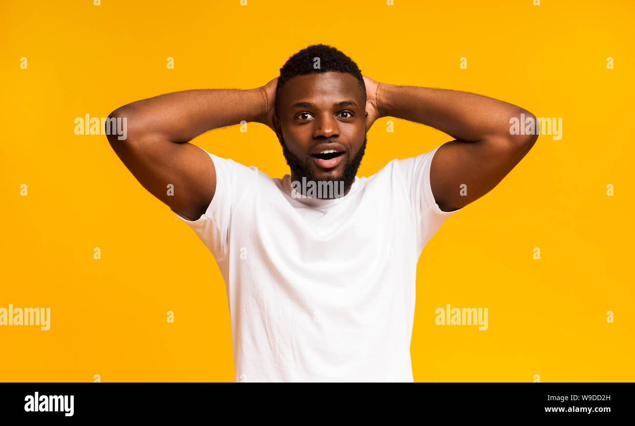 Stupito uomo africano tenendo le mani dietro la testa Foto Stock