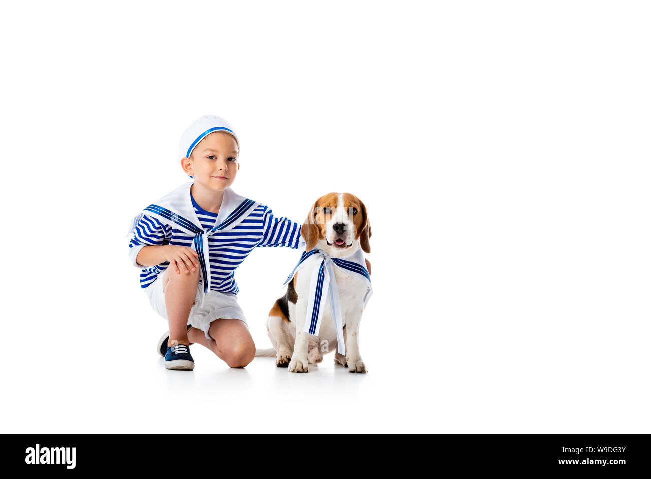 Preschooler sorridente bambino in costume da marinaio e cane beagle su bianco Foto Stock