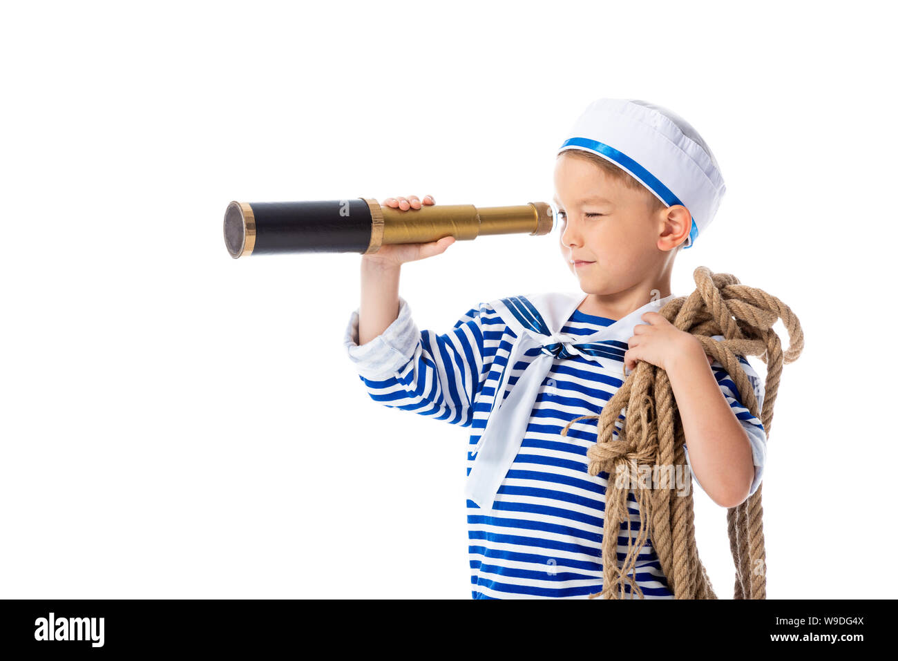 Focalizzato preschooler bambino in costume da marinaio cercando in il cannocchiale e tenendo la corda isolato su bianco Foto Stock